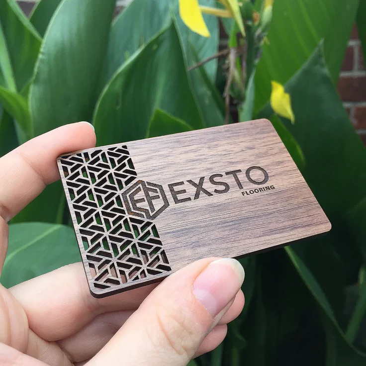 Wooden business card laser-marked with the EXSTO Flooring logo and cut-out pattern